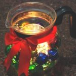 A Glass Tea Kettle is transformed into a glowing centerpiece for a Christmas table.